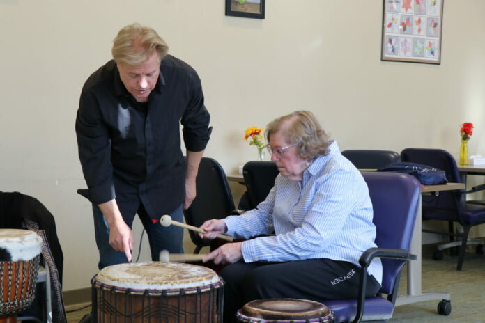 Left to right: Randy Armstrong helps Donna, a participant in Easterseals NH’s Adult Day Program, learn a new drumming technique.